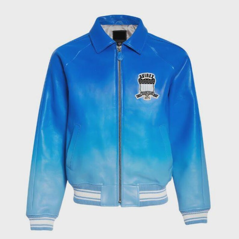 May include: A blue leather jacket with a gradient effect, transitioning from a deep blue at the top to a lighter shade at the bottom. Features a collar, zipper closure, and a patch on the chest with the text "AVIREX". The jacket has white and blue striped cuffs and hem.