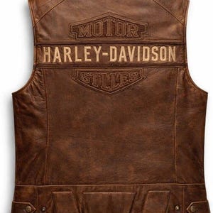 Puede incluir: Chaleco de cuero marrón con el logotipo de Harley-Davidson bordado en la espalda. El chaleco presenta un diseño clásico con un corte entallado y dos bolsillos en la parte inferior. El chaleco está hecho de cuero envejecido.