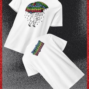 May include: White t-shirts with a graphic of a person under a rainbow umbrella with the text "Dropdead!" The back of one shirt also has the text "Dropdead!" in rainbow colors. The shirts have a V-neck.