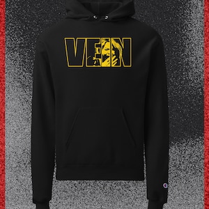 May include: A black hooded sweatshirt featuring a front kangaroo pocket and long sleeves. The chest displays the word VEIN in bold yellow outline lettering, with a yellow graphic of a person covering their face integrated into the letter I.