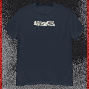 Könnte beinhalten: Ein dunkelblaues T-Shirt mit kurzen Ärmeln und einer rechteckigen Grafik auf der Brust. Die Grafik enthält drei schwarz-weiße Felder mit Musikinstrumenten und dem weißen Schriftzug FENIX TX im rechten Feld.