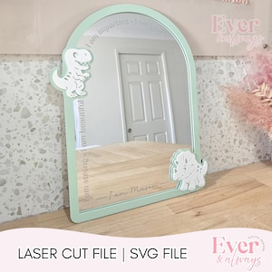 May include: A mint green arched mirror with white dinosaur cutouts. The mirror has engraved text that reads "I am important, I am kind, I am strong, I am beautiful." The text "I am Mason" is also engraved. The bottom of the image reads "LASER CUT FILE | SVG FILE."