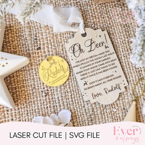 May include: A wooden Christmas ornament and tag set. The tag reads "Oh Deer!" with a poem about a lost name tag. A gold-colored circular ornament has "Rudolf" and "Property of the North Pole" engraved on it.