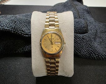 Seiko horloge dames goudkleurig quartz dag datum gekartelde ring vintage 3E23-0A69