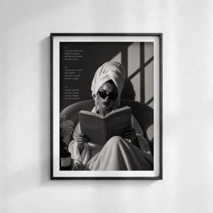 Puede incluir: Impresi&oacute;n en blanco y negro enmarcada que muestra a una persona con gafas de sol y una toalla leyendo un libro. Texto a la izquierda, botella y cuenco sobre una mesa.