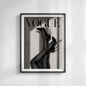 Puede incluir: Impresi&oacute;n enmarcada en blanco y negro de una portada de la revista Vogue. La imagen muestra el logotipo de la revista y las piernas de una persona con tacones altos negros y medias transparentes. Una impresi&oacute;n de tem&aacute;tica de moda.