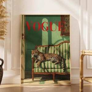 May include: A framed print with a leopard on a green and white striped sofa. The word "VOGUE" is in red at the top. The artwork has a vintage style, with a green background and a gold frame. The image evokes a sense of luxury.