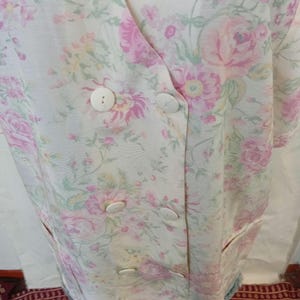 Può includere: Un blazer a fantasia floreale in una morbida palette di colori pastello. La giacca presenta un design doppiopetto con grandi bottoni bianchi rotondi. Il tessuto è ricoperto di rose rosa e gialle con foglie verdi.
