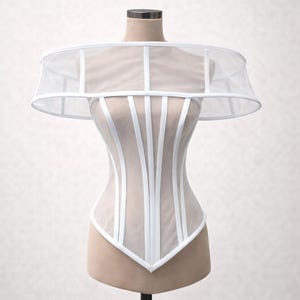 May include: A white corset top featuring sheer mesh panels and structured vertical white boning. The garment includes a wide, circular off-the-shoulder collar piece made of matching sheer mesh and white trim, creating a rigid, architectural silhouette.