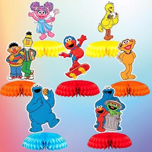 Può includere: Una collezione di ritagli di personaggi di Sesame Street, tra cui Elmo, Cookie Monster e Big Bird, disposti con centrotavola a nido d'ape colorati. I personaggi sono in varie pose, su uno sfondo sfumato.