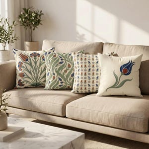 May include: Four square throw pillows arranged on a sofa. The first features a large floral motif with red and blue tulips. The second has a dense green leaf pattern. The third displays a small repeating tulip print. The fourth shows a single blue tulip.