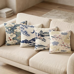 Peut inclure: Quatre coussins décoratifs avec des motifs d'inspiration japonaise sur un canapé beige. Les coussins présentent des motifs de fleurs de cerisier, de montagnes et de vagues stylisées dans des tons de bleu, crème et rouge.