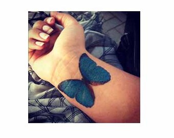 May include: A blue butterfly tattoo on a person's wrist.