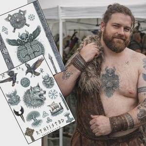 Puede incluir: Dos hojas de tatuajes temporales con diseños vikingos, que incluyen un escudo, hachas, una calavera alada, cuervos, un lobo y un barco vikingo. Los tatuajes son en blanco y negro. Una persona con tatuajes similares está en la imagen.