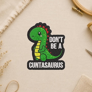 May include: Embroidered patch featuring a green dinosaur with yellow accents and a red spiky back. The patch has the text "DON'T BE A CUNTASAURUS" in white letters on a black background. The dinosaur is smiling.