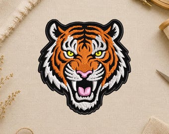 May include: Embroidered tiger head patch with orange, black, white, pink, and yellow details. The tiger is snarling, with its mouth open, teeth bared, and eyes narrowed. The patch has a black border and is set against a neutral background.