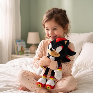 May include: A plush toy of the character Shadow the Hedgehog from the Sonic the Hedgehog franchise. The toy is black with red accents, white gloves, and red and yellow shoes. The plush is held by a person wearing pink pajamas.