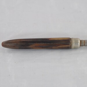 May include: A brown and silver screwdriver with a wooden handle.