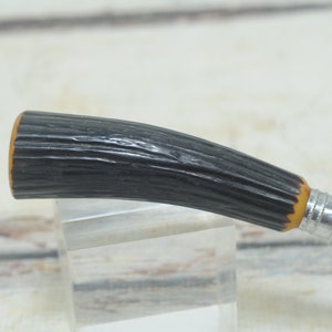 May include: A black and brown handled vintage razor with a metal blade.