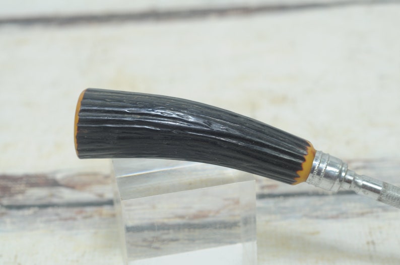 May include: A black and brown handled vintage razor with a metal blade.