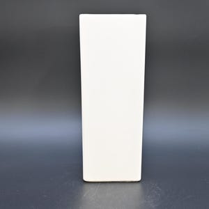 May include: A tall, rectangular, white ceramic vase. The vase has a simple, minimalist design with a smooth, matte finish. It stands upright against a dark gray background, showcasing its clean lines and modern aesthetic.