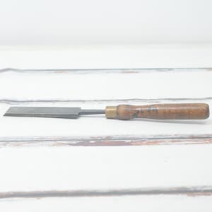 May include: A vintage wood and metal chisel with a brass ferrule and a wooden handle.