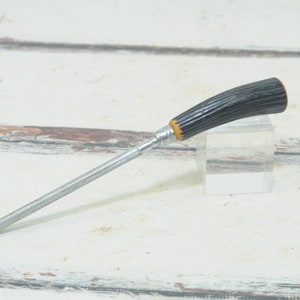 May include: A silver knife sharpener with a black and yellow handle. The handle is made of a textured material that resembles wood.