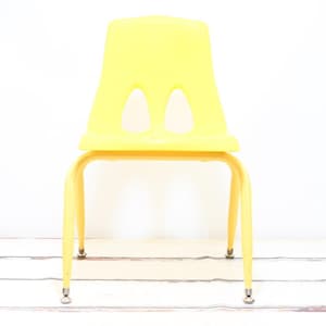 May include: A bright yellow plastic chair with a simple design and four legs. The chair is made of a durable material and is suitable for both indoor and outdoor use.
