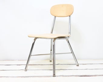 May include: A chrome and wood school chair with a rounded back and a simple design.