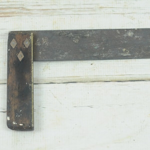 May include: A vintage wooden and metal try square with brass accents. The square has a dark wood handle and a metal blade.