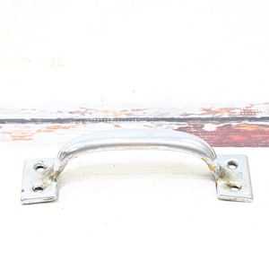 May include: A silver metal handle with two square plates on either end. The handle is curved and has a smooth finish.