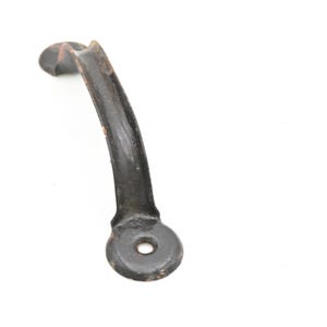 May include: A curved, antique-style black metal handle with a circular base and a hole for mounting. The handle has a slightly distressed appearance, suggesting age or wear. The handle is isolated on a white background.
