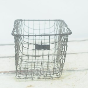 Puede incluir: Una cesta de alambre de metal gris de forma rectangular. La cesta tiene una etiqueta que dice "Jardín".