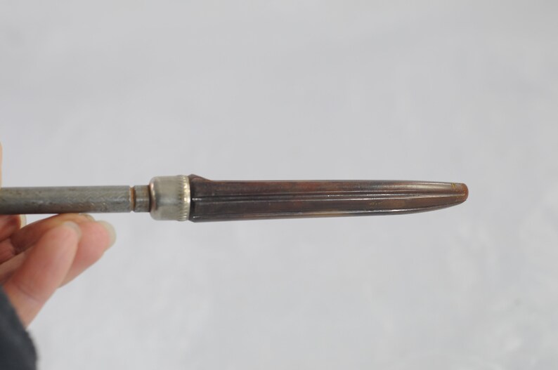 May include: A brown and silver vintage screwdriver with a wooden handle.