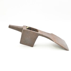 May include: A vintage, rusty brown axe head with a rectangular blade and a curved handle. The axe head has a rectangular eye for the handle and is set against a white background.