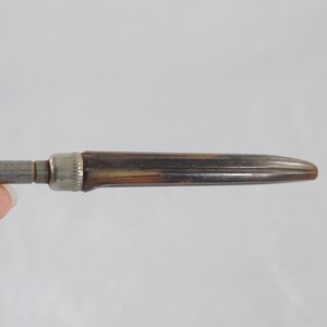 May include: A silver and brown metal pencil sharpener with a metal blade and a wooden handle.