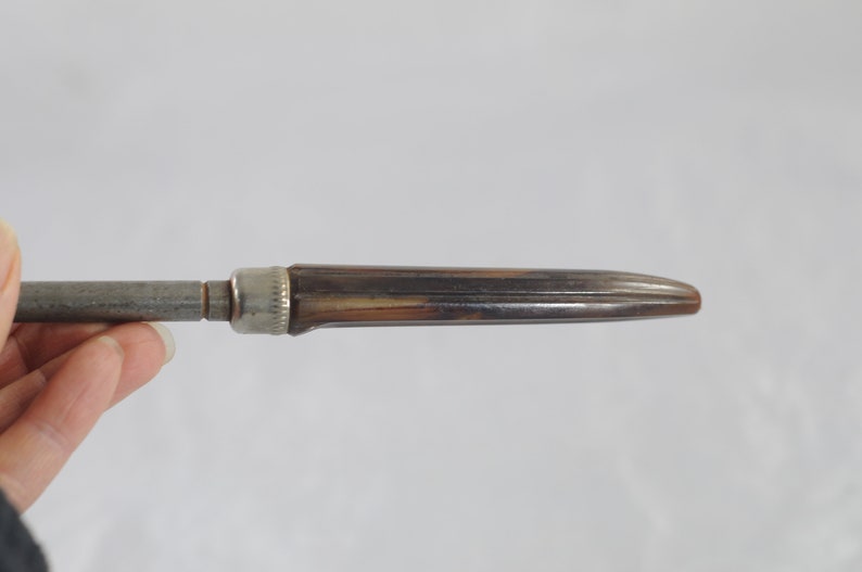 May include: A silver and brown metal pencil sharpener with a metal blade and a wooden handle.