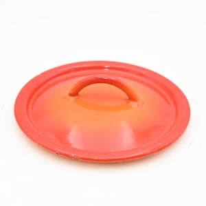 May include: Orange enamel cast iron pot lid with a single handle.
