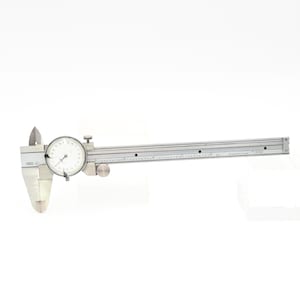 May include: A silver metal caliper with a dial gauge and a ruler. The caliper is used for measuring the length of objects.