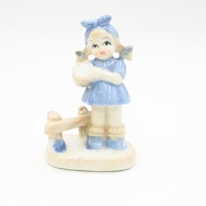 Vintage . Small Girl Porcelain Figurine Blue and White Dutch Girl Next to Fence With Pie
