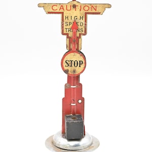 May include: Vintage metal railroad crossing sign with the words "CAUTION", "HIGH SPEED TRAINS", and "STOP". The sign is red, yellow, and black, with a circular "STOP" sign. The base is silver and the sign is on a white background.