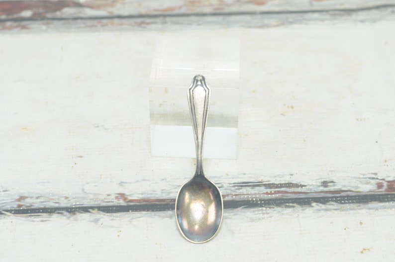 May include: A silver teaspoon with a rounded bowl and a simple, elegant design.