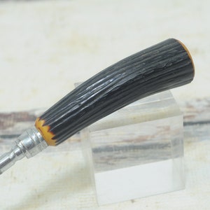 May include: A black and brown handled knife sharpener with a metal shaft.