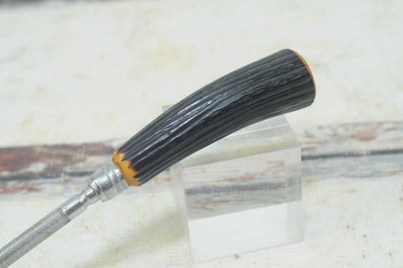 May include: A black and brown handled knife sharpener with a metal shaft.