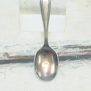 May include: A silver teaspoon with a rounded bowl and a simple, elegant design.