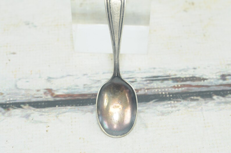 May include: A silver teaspoon with a rounded bowl and a simple, elegant design.