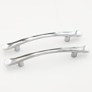 May include: Two silver-colored cabinet handles with a curved design. Each handle has a rounded center and two cylindrical posts for mounting. The handles are made of a shiny metal and are set against a white background.