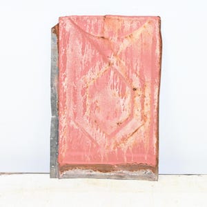 May include: A rectangular metal panel, showing signs of age with a faded pink colour and a diamond pattern. The panel has rust and a silver metal edge. The design suggests an antique or industrial theme.