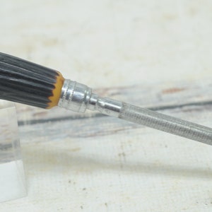 May include: A metal file with a black and brown stag horn handle. The file is used for sharpening knives.
