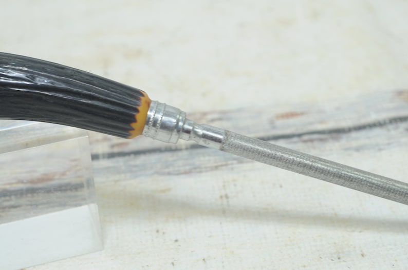 May include: A metal file with a black and brown stag horn handle. The file is used for sharpening knives.
